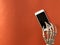 Skeleton using smartphone on orange background