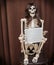 Skeleton in a wig sitting on the chair and holding paper with written message