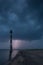 Skew lighthouse in the Baltic Sea. Stormy night and lightning.