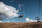 Ski chair-lift in front of blue sky in sunny day. No people. Elevator in autumn