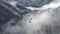 Ski elevator moving over white snowy mountain cloud forest in lowland. Drone view ski lift transporting skiers and snowboarders to