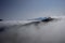 A ski lift above the clouds in the morning mist