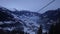 Ski lift on a background of snow-capped mountains and valley. Empty chairs move against the backdrop of a beautiful