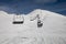 Ski lift empty ropeway on hilghland alpine mountain winter resort on bright sunny day.