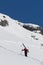 Ski patrol climbing up a mountain slope carrying large skis