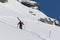 Ski patrol climbing up a mountain slope carrying large skis