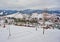 Ski resort in beautiful sunset light. View from the top: ski tracks, pine tree forest and mountains in the background