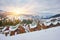 Ski resort in beautiful sunset light. View from the top: ski tracks, pine tree forest and mountains in the background