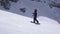 Ski resort. Happy snowboarder ride on slope, abruptly breaks. Spray of snow. Sun