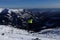 Ski rider enjoys jumping on big bump. Young teenager in colored jacket skiing on fresh powder snow with valley in background,