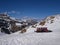 Ski slope in italian Dolomites - rocky snowy mountains, blue sky and snow groomers