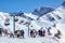 Ski and snowboard mountain resort Gorky Gorod. People hang out on ski lift and snowy Aibga mountain peaks sunny background