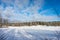 Ski track trail on the snow field. Skiers ride on winter day. Healthy people lifestyle. The edge of evergreens forest with rows of