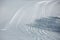 Ski tracks on a sunny winter slope. The shadow of the tree on the track. France, Savoie, Bessans