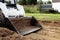 A skid steer loader clears the site for construction. Land work by the territory improvement. Machine for work in confined areas.