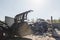 Skid steer loader moving waste material, shaking out a scrap grapple