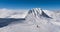 A skier alone on the ski slopes with summits and blue sky