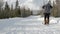Skier beginner with large backpack crosses snowy track