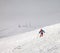 Skier descent on snowy freeride slope and overcast misty sky