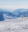 Skier downhill on snowy slope and mountains in haze at cold winter day