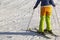 Skier in full gear and bright clothes stands in the snow on a sunny day.