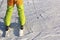 Skier in full gear and bright clothes stands in the snow on a sunny day.
