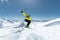 A skier in full sports equipment jumps into the abyss from the top of the glacier against the background of the blue sky