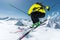 A skier in full sports equipment jumps into the abyss from the top of the glacier against the background of the blue sky