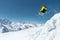 A skier in full sports equipment jumps into the precipice from the top of the glacier against the background of the blue