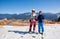 Skier girl and boy on skis on background of winter resort, bright blue sky and beautiful mountains.