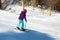 Skier girl performing slalom ride and having fun at resork in winter from the back