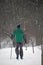 Skier in a green suit, rides in the park during a snowstorm