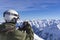 Skier man with orange ski glasses in white helmet make photoshoot on top in Alps mountains. On the background of