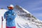 Skier man with orange ski glasses in white helmet make photoshoot on top in Alps mountains. On the background of mountains. Close