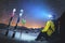 A skier sits at a stone in the mountains at night against a starry sky next to skis and sticks. The concept of extreme