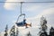 Skier sitting at ski lift against blue sky