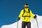 Skier standing on a slope. Man in a light suit, the helmet and mask in skiing is to ski. In the background snow-capped