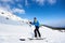 Skier tourist with backpack on background of bright blue sky and beautiful mountain panorama.