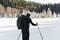 Skier tourist with a backpack on a frozen lake in the woods