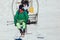 Skier wearing skis, helmet and mask sitting in ski lift