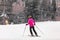 Skier woman skiing learning to ski on mountain slope. Winter sport outdoor activity. Girl from behind in pink jacket and