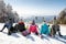 Skiers sitting on snow and looking landscape, back view