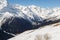 Skiers and snowboarders ride on the snowy slopes against the background of the peaks of the Caucasus Mountains