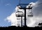 Skiing chairlift silhouette against blue sky and white clouds.