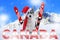 Skiing malamute dog sitting in the snow wearing a santa hat and scarf