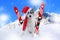 Skiing malamute dog sitting in the snow wearing a santa hat and scarf