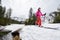 Skiing off-piste on foothill plain. Skiers during ski touring over flowing river, low angle. Mountains under grey sky