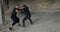 Skilful fighting of two angry men in black clothes in an abandoned building