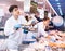 Skilful shop assistant weighing cod fish on scales in fish store