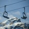 Skilift and chair lifts at ski resort against snowy mountains in winter.